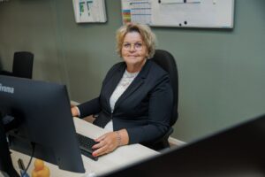 Laptop, collega achter laptop kijkend in camera, vrouw